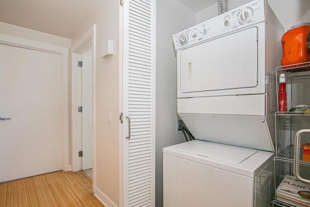 laundry room with light hardwood / wood-style flooring and stacked washer and clothes dryer