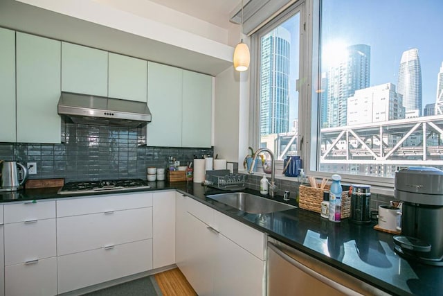 kitchen with stainless steel gas stovetop, ventilation hood, white cabinets, sink, and a healthy amount of sunlight