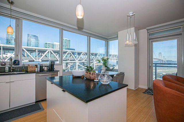 kitchen featuring white cabinets, stainless steel dishwasher, hanging light fixtures, and sink