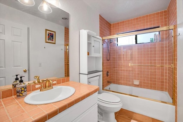 full bathroom featuring toilet, bath / shower combo with glass door, tile patterned floors, and vanity