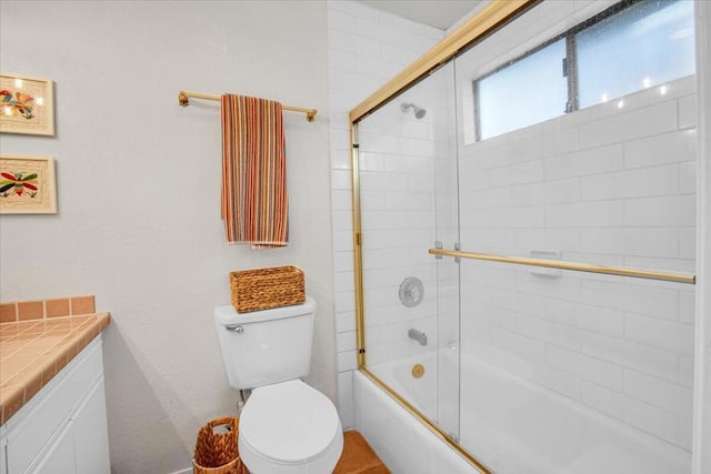 full bathroom featuring toilet, combined bath / shower with glass door, and vanity