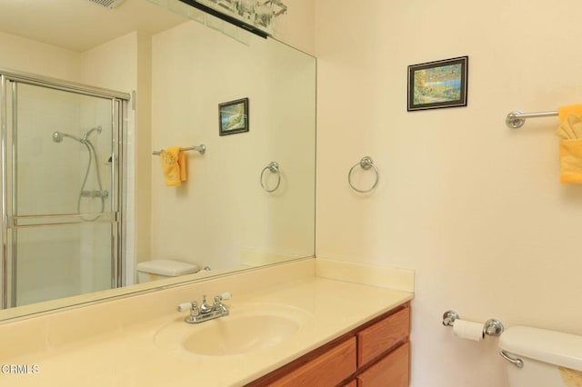 bathroom featuring toilet, a shower with door, and vanity