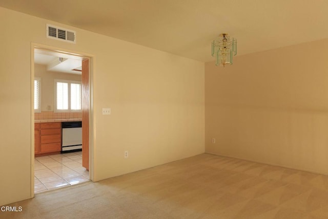 carpeted empty room featuring a chandelier