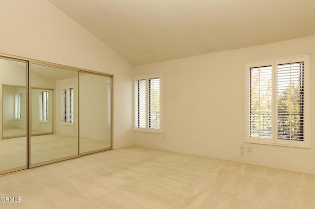 unfurnished bedroom with a closet, lofted ceiling, and light colored carpet