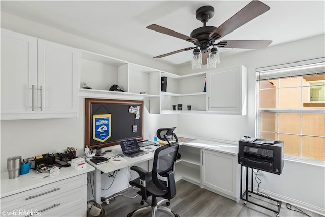 office area featuring ceiling fan, plenty of natural light, built in desk, and light hardwood / wood-style floors