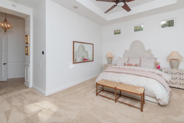 bedroom featuring ceiling fan with notable chandelier, a tray ceiling, and carpet floors