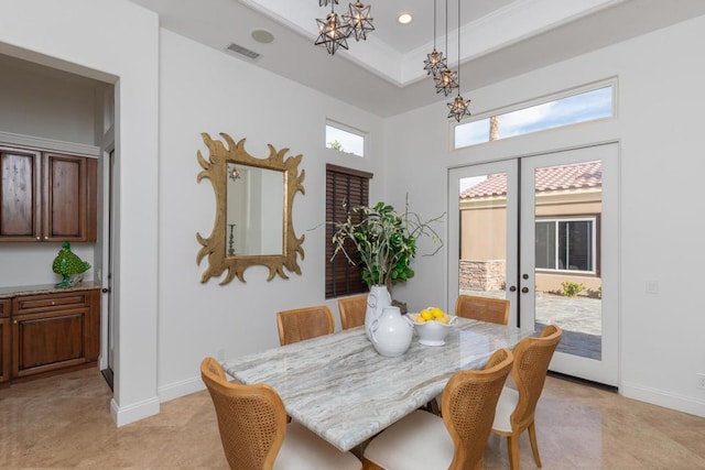 dining room with an inviting chandelier, ornamental molding, a raised ceiling, and french doors