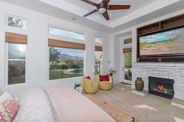 carpeted bedroom with ceiling fan, access to exterior, and a stone fireplace