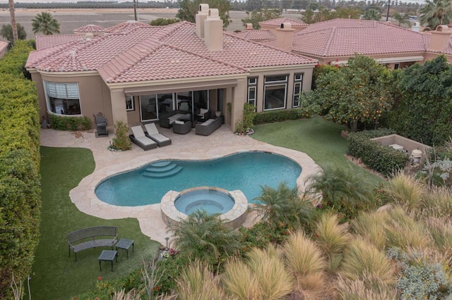 view of pool with an in ground hot tub, a patio area, outdoor lounge area, a lawn, and grilling area