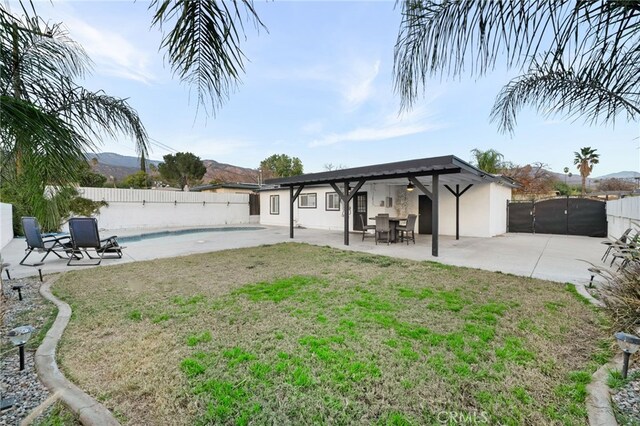 back of property with a fenced in pool, a mountain view, a lawn, and a patio