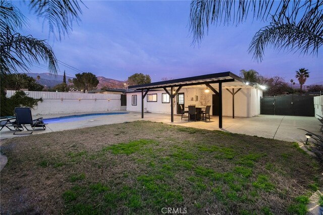 yard at dusk featuring a fenced in pool and a patio