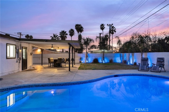 pool at dusk with a patio area