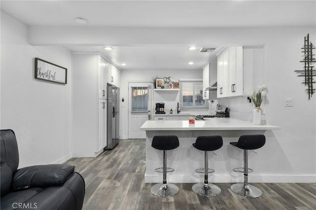 kitchen with kitchen peninsula, a kitchen bar, sink, appliances with stainless steel finishes, and white cabinets