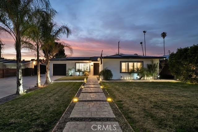 single story home featuring a garage and a yard