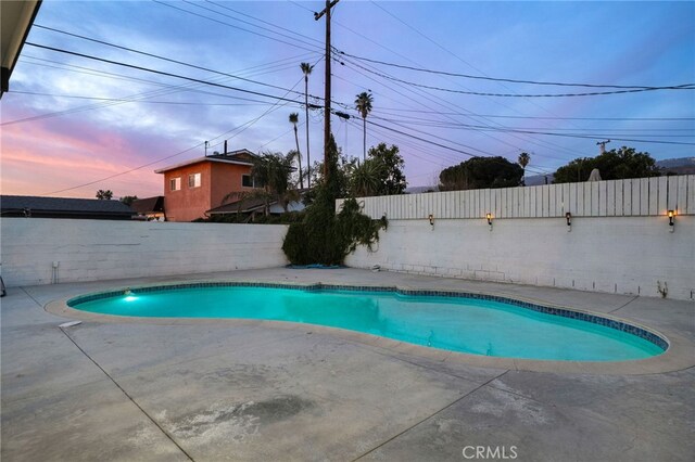 pool at dusk featuring a patio area