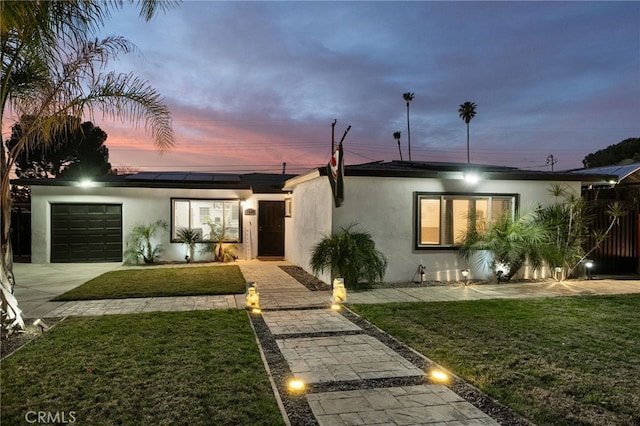 view of front of home featuring solar panels, a yard, and a garage