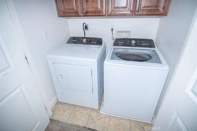 laundry room with cabinets, light tile patterned floors, and separate washer and dryer