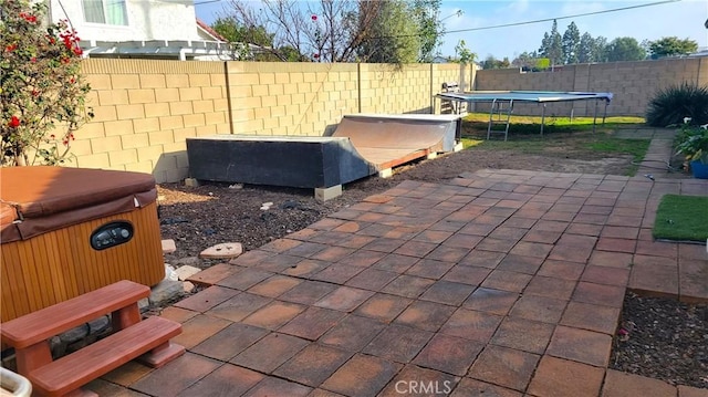 view of patio / terrace featuring a trampoline and a hot tub