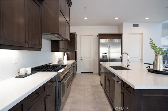 kitchen featuring sink, ventilation hood, light tile patterned floors, a center island with sink, and high quality appliances