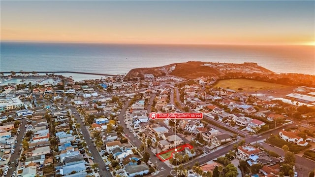 aerial view at dusk featuring a water view