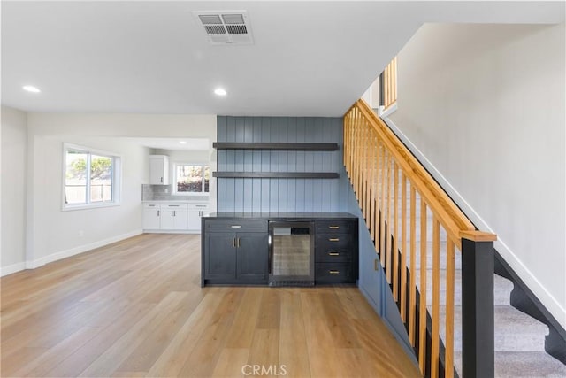 bar featuring wine cooler, white cabinets, tasteful backsplash, and light hardwood / wood-style floors