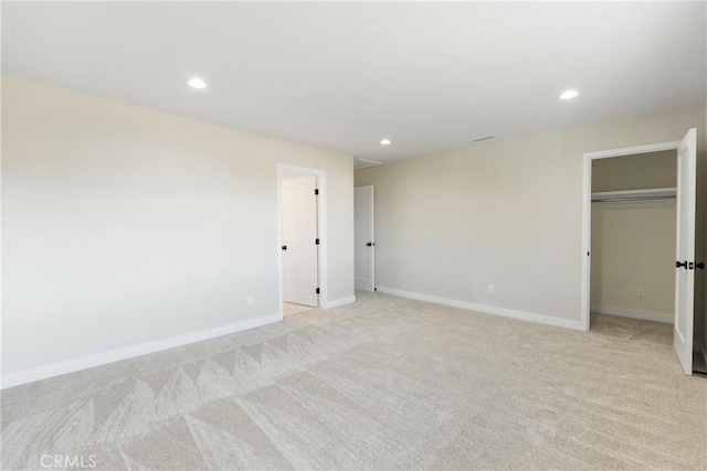 unfurnished bedroom featuring light colored carpet and a closet