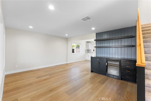 bar with wine cooler and light hardwood / wood-style floors