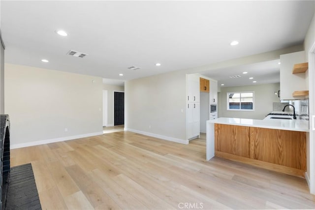 kitchen with light hardwood / wood-style floors, kitchen peninsula, and sink