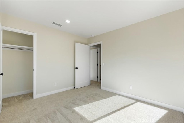 unfurnished bedroom featuring light carpet and a closet