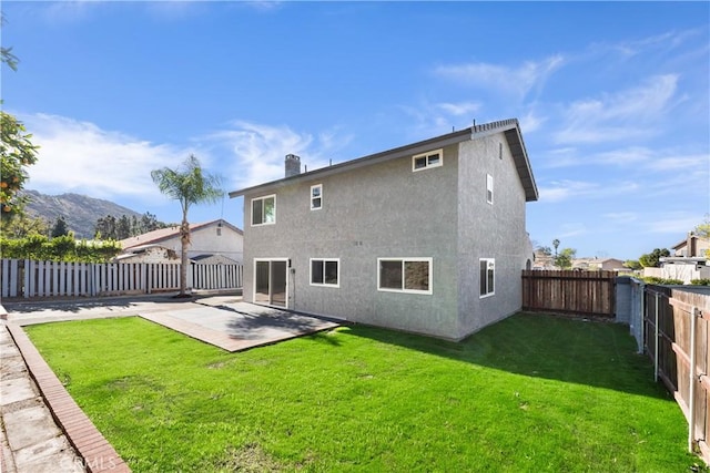 rear view of property with a mountain view, a yard, and a patio