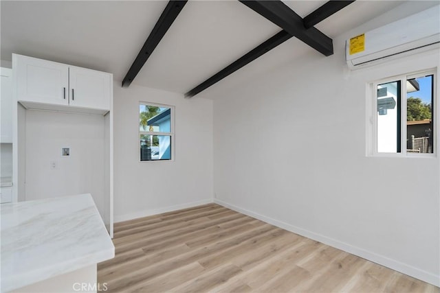 unfurnished dining area with light hardwood / wood-style floors, a wall unit AC, and vaulted ceiling with beams