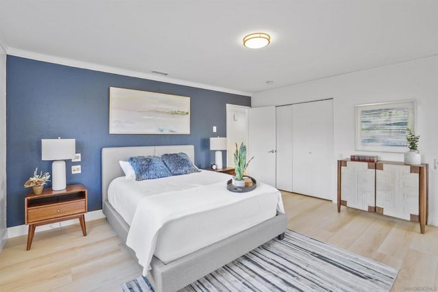 bedroom featuring light hardwood / wood-style floors, ornamental molding, and a closet