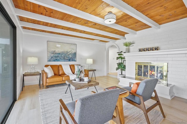 living room with beam ceiling, light wood-type flooring, and a fireplace