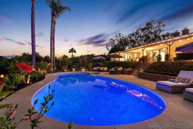 pool at dusk with a patio area