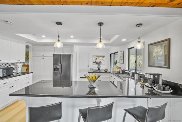 kitchen featuring stainless steel refrigerator with ice dispenser, white cabinetry, and a tray ceiling