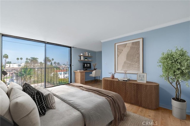 bedroom with baseboards, light wood-style floors, a wall of windows, and crown molding