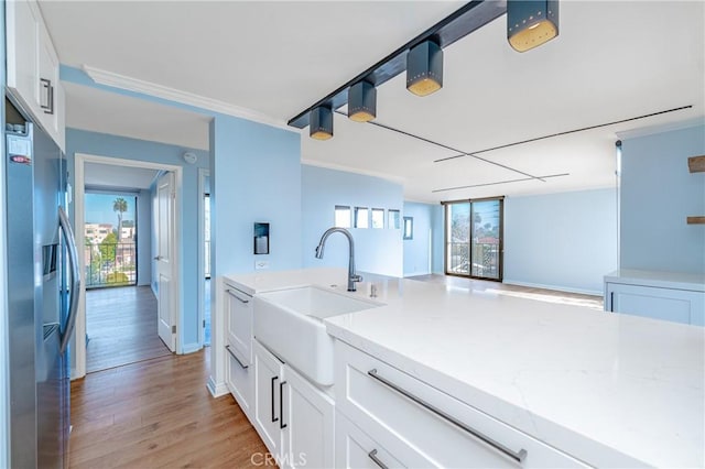 kitchen featuring light stone counters, light wood-style floors, white cabinets, a sink, and stainless steel fridge with ice dispenser