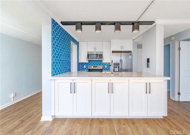 kitchen featuring stainless steel appliances, light countertops, backsplash, and white cabinetry