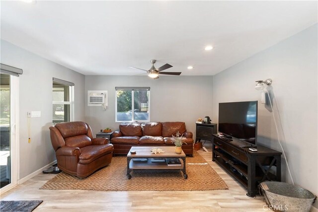 living room featuring light hardwood / wood-style floors, a wall mounted AC, and ceiling fan