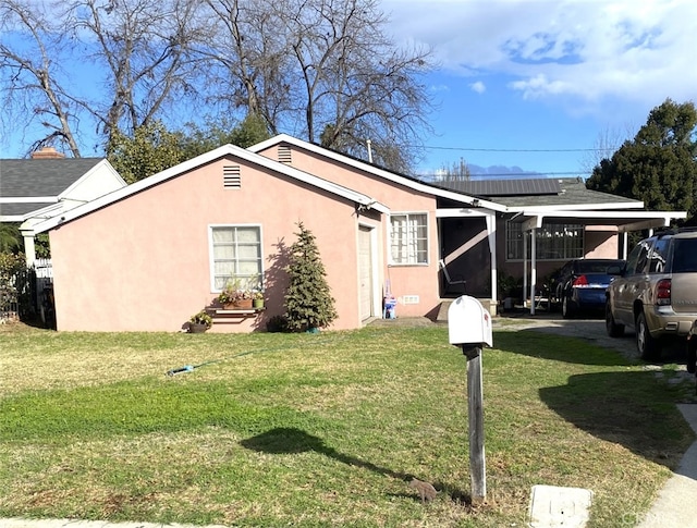 view of side of property featuring a carport, a yard, and solar panels