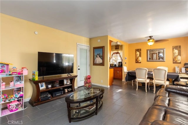 living room featuring ceiling fan and dark tile patterned floors