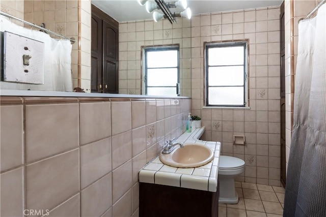 bathroom with toilet, vanity, tile walls, tasteful backsplash, and tile patterned flooring