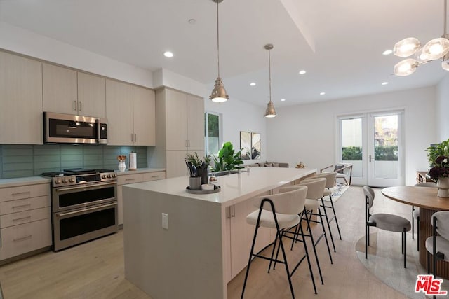 kitchen featuring pendant lighting, a kitchen island, cream cabinetry, and appliances with stainless steel finishes