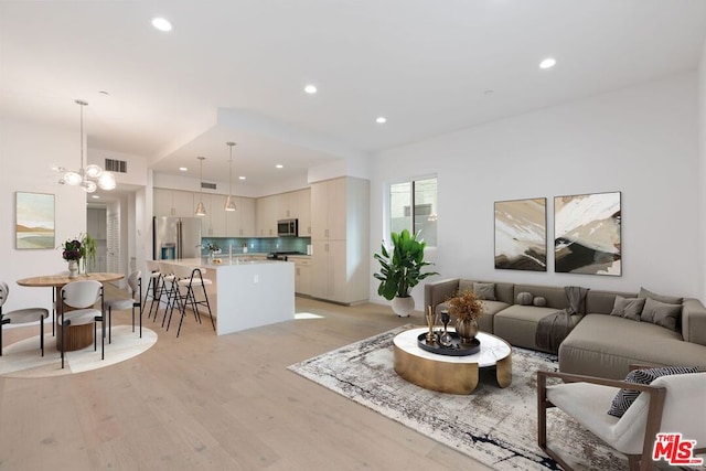 living room with an inviting chandelier and light hardwood / wood-style floors