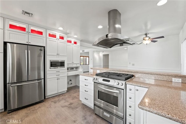 kitchen featuring stainless steel appliances, island range hood, white cabinetry, and light stone counters