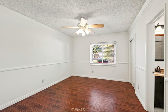 empty room featuring a textured ceiling, ceiling fan, ornamental molding, and dark hardwood / wood-style flooring