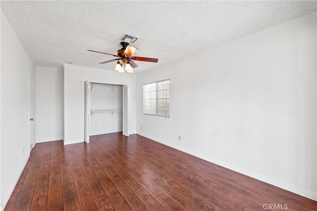 unfurnished bedroom featuring a textured ceiling, ceiling fan, a closet, and dark hardwood / wood-style floors