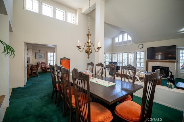 carpeted dining room featuring an inviting chandelier, a healthy amount of sunlight, and a high ceiling