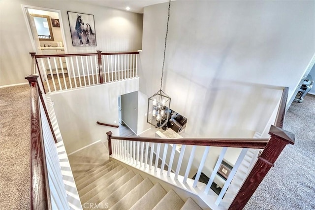 staircase featuring carpet and a chandelier