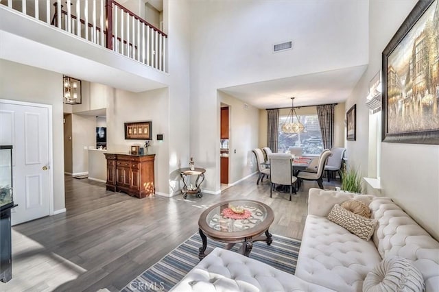 living room with a high ceiling, hardwood / wood-style floors, and a notable chandelier